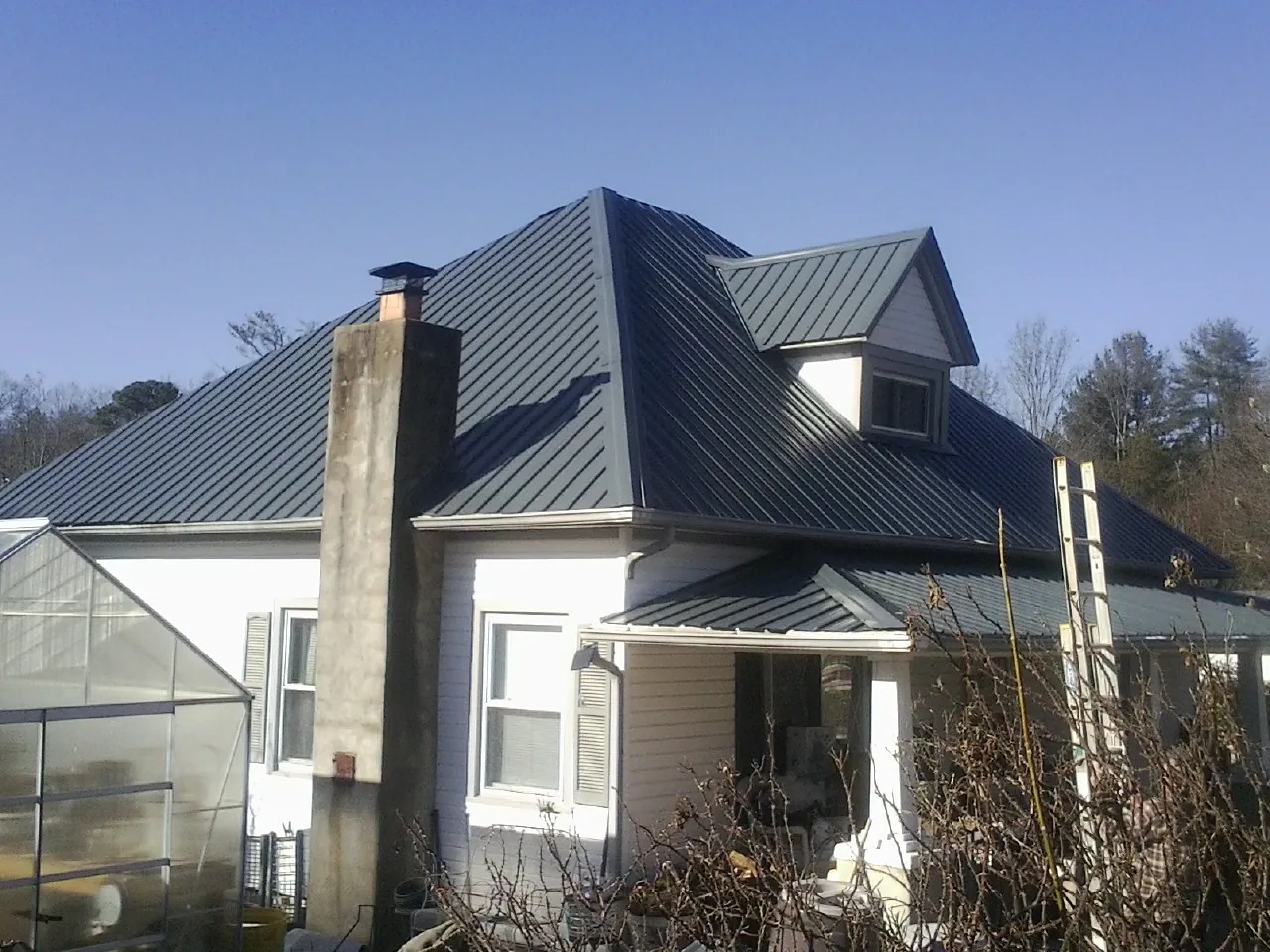 Dark blue standing seam metal roof on a white farmhouse with dormer — Slate & Tile Roof Repair by Roofing Brothers in North Versailles