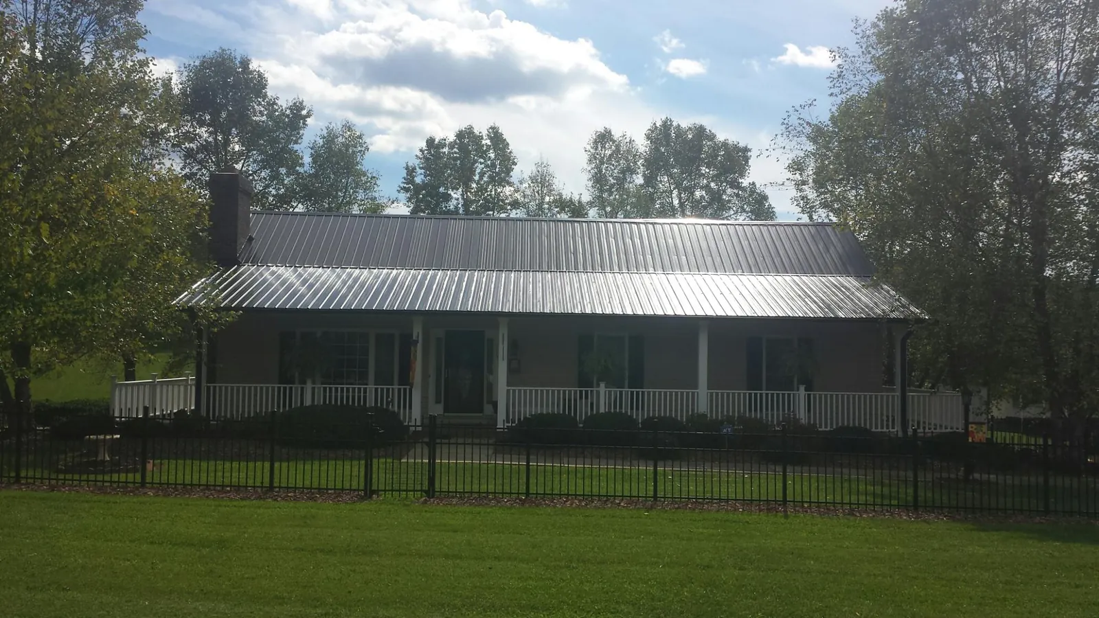 Gray metal roof on a brick ranch with a full width front porch — Gutter Guard Installation work by our crew in North Versailles