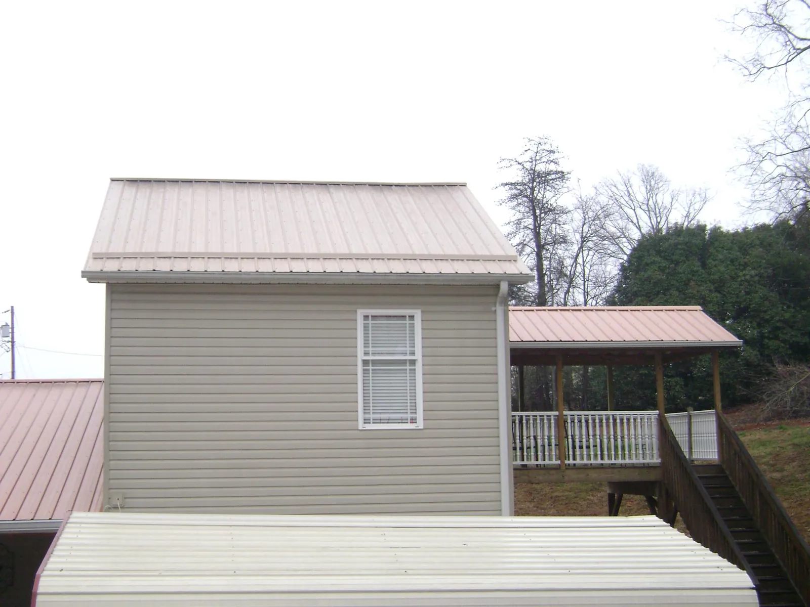 Tan metal roofs on a two story addition and attached porch, from a Roof Replacement job in North Versailles