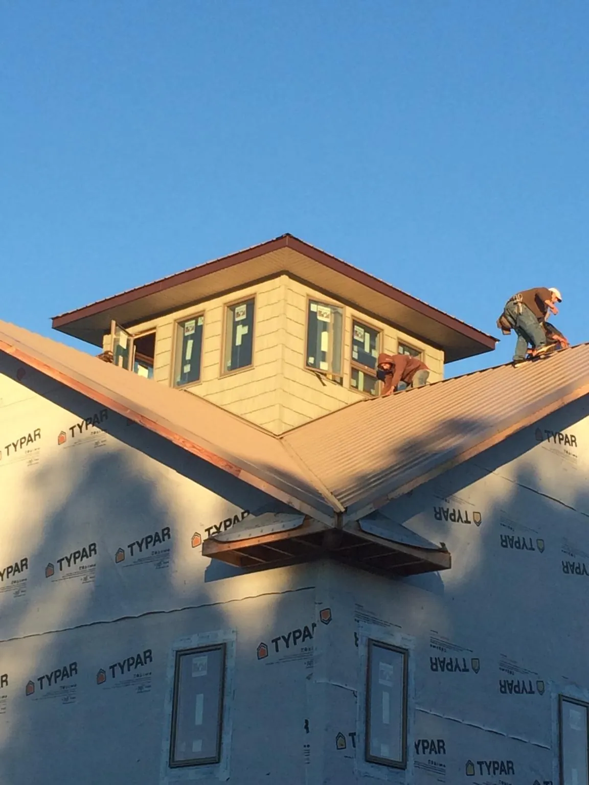 Roofers working around a rooftop cupola on a new metal roof at sunset — Roof Waterproofing in North Versailles by Roofing Brothers